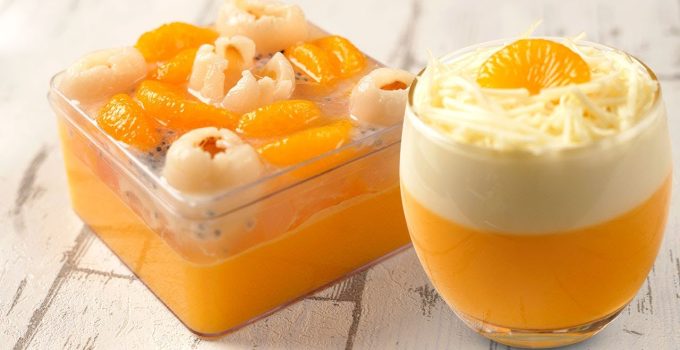 Puding mangga keju lembut dengan lapisan warna cerah, dihias daun mint untuk sentuhan elegan