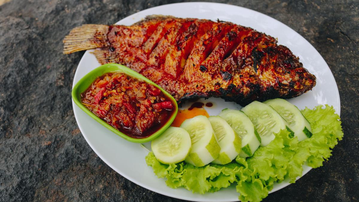 Sepiring ikan nila rica pedas dengan bumbu rica khas Manado, disajikan bersama nasi putih dan lalapan segar