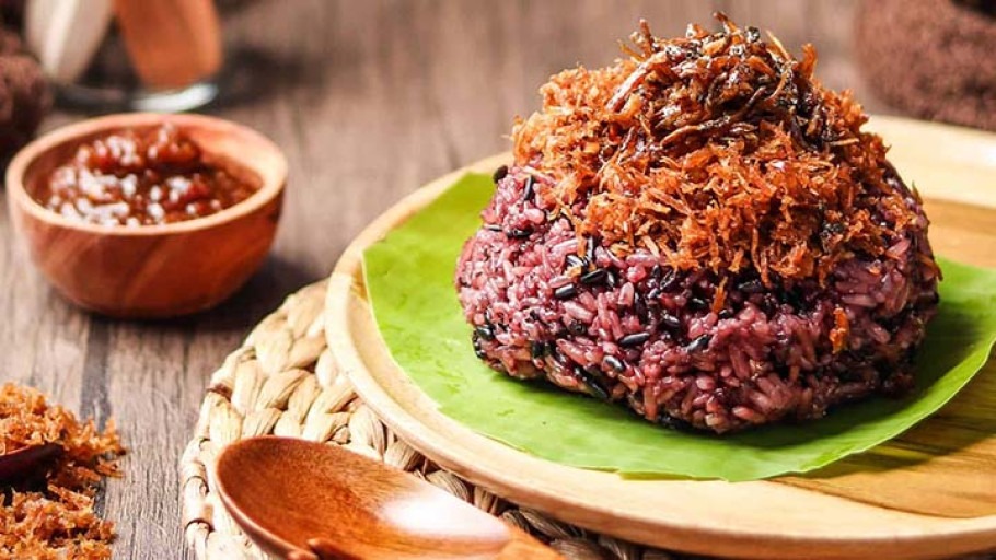 Sepiring Songkolo Hitam khas Makassar tersaji dengan ketan hitam yang pulen, kelapa parut gurih, dan pelengkap ikan teri goreng serta telur asin